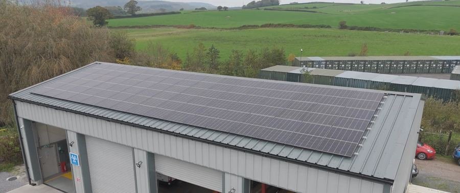 Solar panels on a commercial garage roof beside green fields